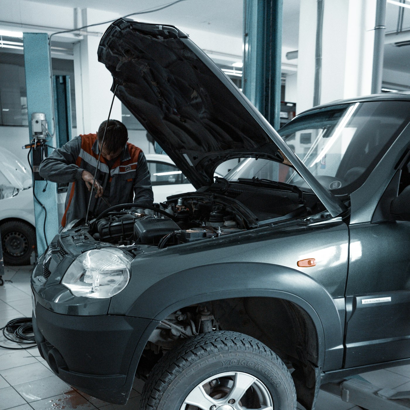 Mechanic working under the hood of an SUV in a shop bay